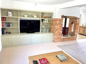 a living room with a large entertainment center with a flat screen tv at Meadow Cottage in Hampshire's Test Valley in Andover