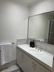 ein Badezimmer mit einem weißen Waschbecken und einem Spiegel in der Unterkunft Free secure parking & WiFi in this Executive 3 BR. in Kalgoorlie