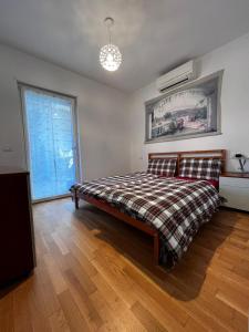a bedroom with a bed with a plaid blanket and a window at Garden & Pool Perugini in Nago-Torbole