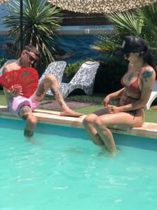 un hombre y una mujer sentados junto a una piscina en Hosteria Villa del Lago en Villa Carlos Paz