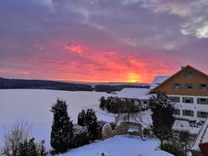 a sunset over a snow covered lake in front of a building at Apartment Auszeit mit Küche viel Ruhe und Natur in Untrasried