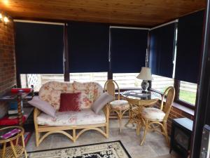 a screened in porch with a couch and a table at The Catkins, Grove flock farm in Diss