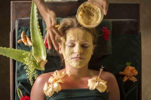 Eine Frau mit einer goldenen Gesichtsmaske auf dem Kopf. in der Unterkunft Ayurveda Paradise Maho in Yapahuwa