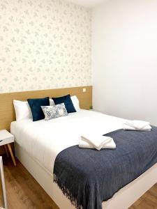een slaapkamer met een groot wit bed en een blauwe deken bij Apartamentos Fuencarral II in Madrid