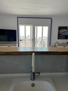 a bathroom with a sink and a window and a television at Apartamento con vistas al mar in Cambrils