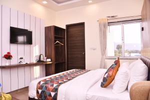 ein Hotelzimmer mit einem Bett und einem TV in der Unterkunft Hotel Saif Ranthambhore in Sawāi Mādhopur