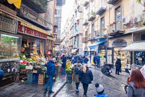 a group of people walking down a street in a market at San Liborio bed and breakfast in Naples