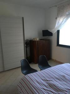 1 dormitorio con 2 sillas, 1 cama y TV en GIARDINI VERDI Intero appartamento, en Muravera