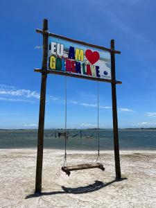 un cartel en la playa con un columpio en Golden Lake - Vista Lagoa, en Arraial do Cabo