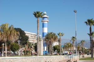 a lighthouse in the middle of a beach with palm trees at Atico cerca del mar con vistas in Torre del Mar