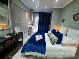een slaapkamer met een groot bed met blauwe en witte kussens bij Rus 'n Bietjie in Bothaville