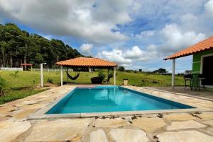 a swimming pool in a yard with an umbrella at Pousada Sal da Terra in Carrancas