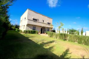 een groot wit huis met een grasveld ervoor bij Villa Nour Al-Khalil in Essaouira