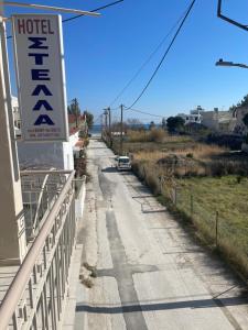 una carretera con un cartel de hotel en una valla en Hotel Stella, en Volos