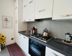 La cuisine est équipée de placards blancs et d'un four avec plaques de cuisson noires. dans l'établissement Appartamento Magnolia Residenza Prealba, à Levanto