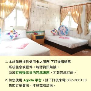 2 camas en una habitación con escritura en la pared en Hsin Hsin Hotel, en Miaoli