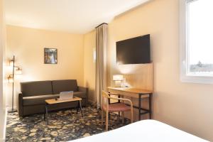 a hotel room with a couch and a desk with a laptop at ibis Styles Versailles Saint Quentin en Yvelines in Saint-Cyr-lʼÉcole