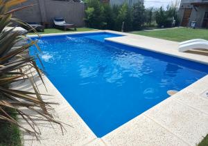 a swimming pool with blue water in a yard at Hospedaje MP canning in Ezeiza