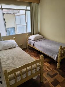 una piccola camera con due letti e una finestra di Vicz Palace Hotel a Curitiba