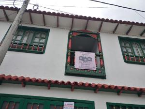 een gebouw met groene ramen en een bord erop bij ApartaHotel Monguí in Monguí