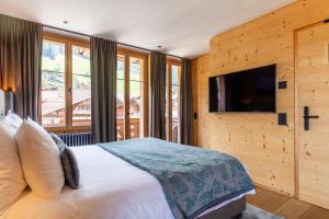 um quarto com uma cama grande e uma televisão em Hotel-Restaurant Valrose em Gstaad