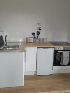 a kitchen with white cabinets and a sink at Lealt Falls Apartment in Culnacnoc