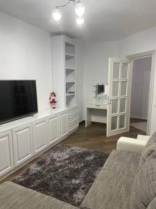 a white living room with a tv and a couch at Lovely 1 bedroom apartment with parking in Iaşi