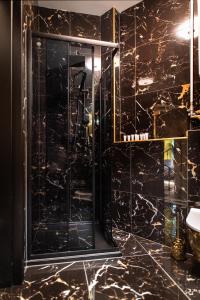 a black bathroom with a shower with a glass door at Jungle Apartments Podwale in Wrocław