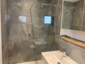 a bathroom with a shower and a sink and a mirror at Dockside Sleeps 8, Uber Boat to Canary Wharf in 3 mins in London