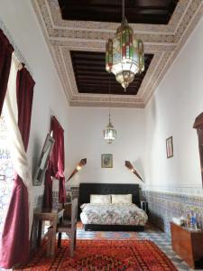 a bedroom with a bed and a chandelier at Riad Freija-TAROUDANT in Sidi Abd el Kader