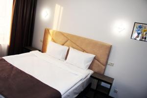 Habitación de hotel con cama con sábanas y almohadas blancas en Nice Hotel Yerevan en Ereván