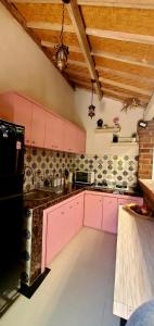 cocina con armarios rosados y nevera negra en Your Secret Garden Villa - Melasti Beach! en Ungasan