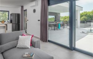 ein Wohnzimmer mit einem grauen Sofa und einer Glasschiebetür in der Unterkunft Amazing Home In Rebici With Outdoor Swimming Pool in Rebići