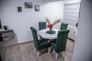 a dining room with a white table and green chairs at Happy in Pirot