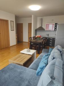 - un salon avec un canapé bleu et une table dans l'établissement Klaipėdos 99 Apartamentai, à Panevėžys