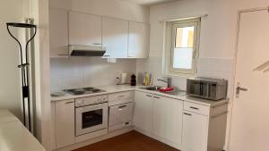 a small kitchen with white cabinets and a microwave at AsconaDolceVita in Ascona