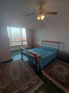 a bedroom with a bed with a fan and a window at شقة ايفو ترى المنتزه بالكامل in Alexandria