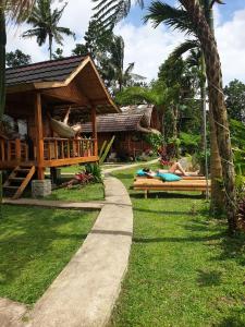 a resort with people laying on benches in the grass at Tetebatu Sama Sama Bungalows in Tetebatu