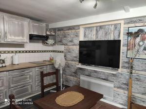 cocina con TV de pantalla plana en la pared en Maison avec deux chambres au calme, en Milly-la-Forêt