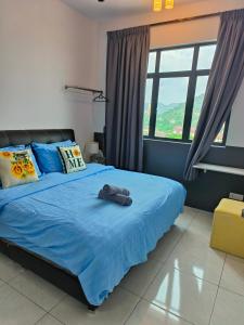 a bedroom with a bed with blue sheets and windows at The Sun 1 or 3BR Bayan Lepas 4 to 10 pax in Bayan Lepas