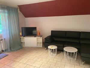 a living room with a black couch and two tables at Hotel Specht in Witten