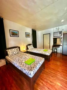 two beds in a room with wooden floors at West Side Cabana in Moalboal