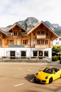 Une voiture jaune conduisant dans une rue devant un bâtiment dans l'établissement Hotel-Restaurant Valrose, à Gstaad