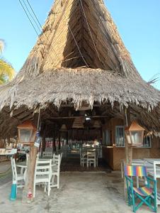 Cabaña de paja grande con sillas y mesas blancas en Al lado del mar, Cabañas Polaris, Coveñas, en Coveñas