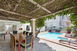 een patio met een tafel en stoelen en een zwembad bij Leighwood Lodge in Johannesburg