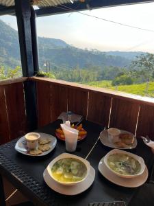 Finca El Encanto del Guejar في Lejanías: طاولة مع أطباق من الطعام وأكواب من القهوة