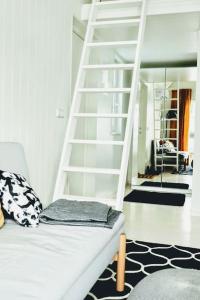 um quarto com uma escada branca e um sofá com uma escada em Charming little country house in central Älmhult em Älmhult
