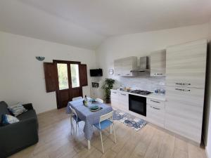 a kitchen with a small table and a kitchen with a couch at Il Melograno casa vacanze in Teulada