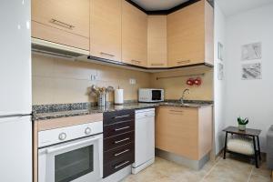 Encantador apartamento en El Delta del Ebro-Apartaments Iaio Kiko في El Lligallo del Gànguil: مطبخ مع أجهزة بيضاء ودواليب خشبية