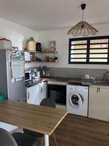 eine Küche mit einer Waschmaschine und einem Holztisch in der Unterkunft L'Octan Océan in Saint-Leu